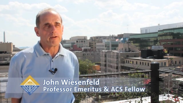 ohn Wiesenfeld, Professor Emeritus and ACS Fellow, speaks on a rooftop with the Washington Monument visible in the background.