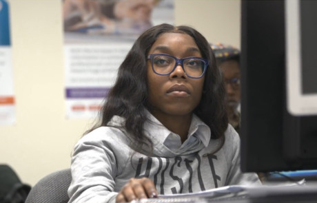 nonprofit fundraising video IT student at computer statio listening to off screen instructor