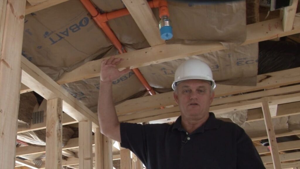 A man standing in a unfinished building with wooden studs showing in the background