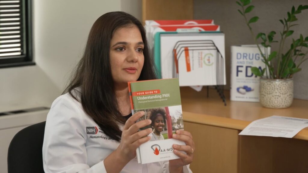 A women sitting down with a book sh eis holding up in her hands, she is wearing a white doctors coat | health and medical video production Washington DC