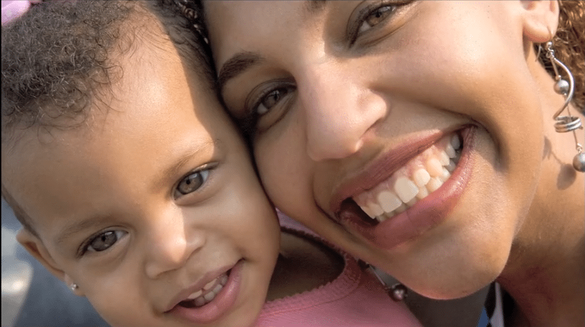 A close-up of a smiling woman and a young child with their heads together