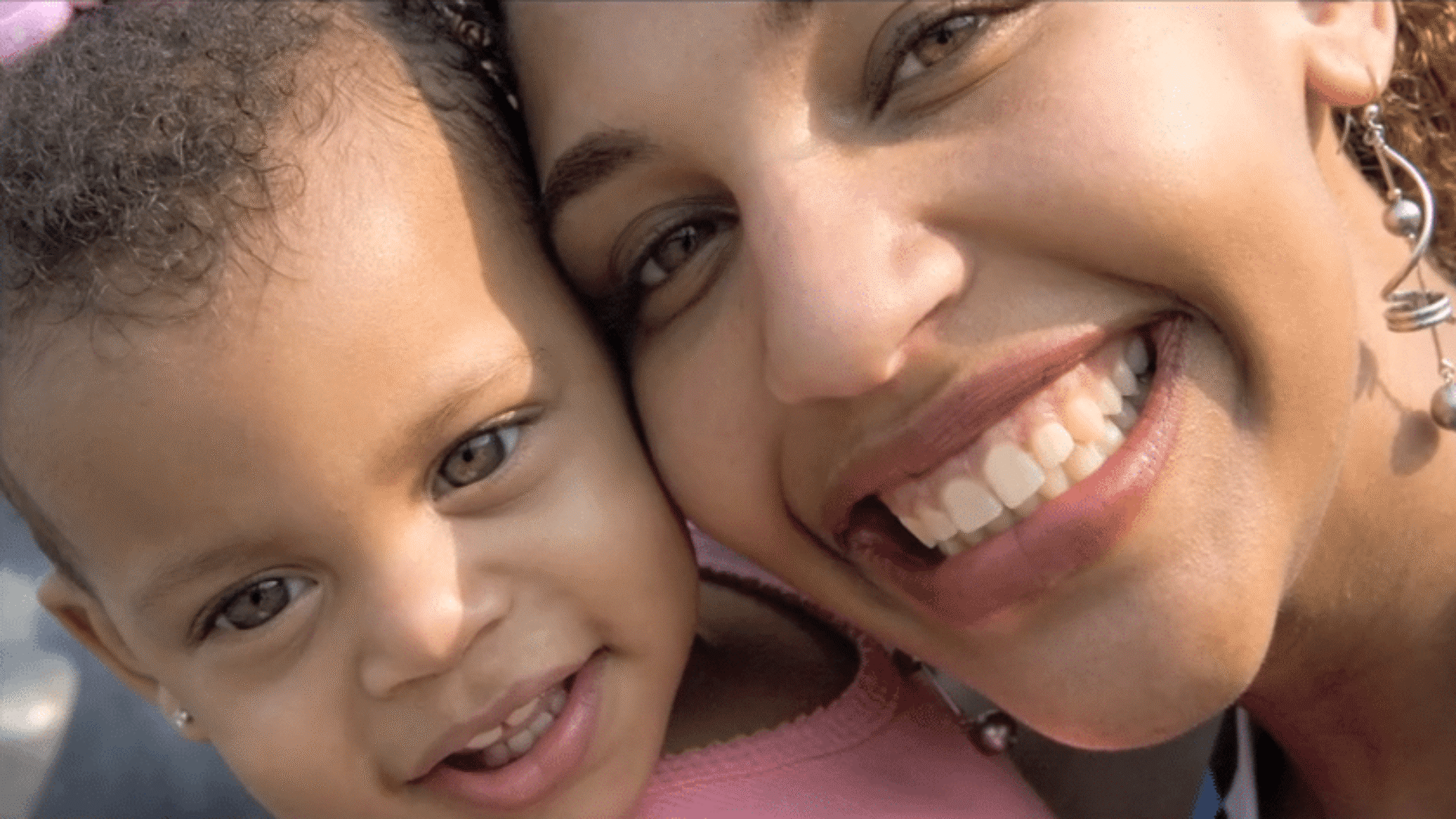 A close-up of a smiling woman and a young child with their heads together